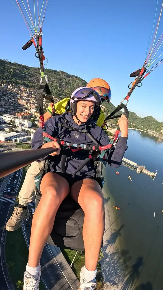 Passageiro sorrindo durante o voo de parapente sobre Niterói