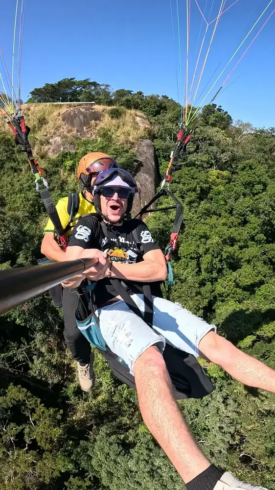 Passageiro registrando o voo de parapente com bastão de selfie