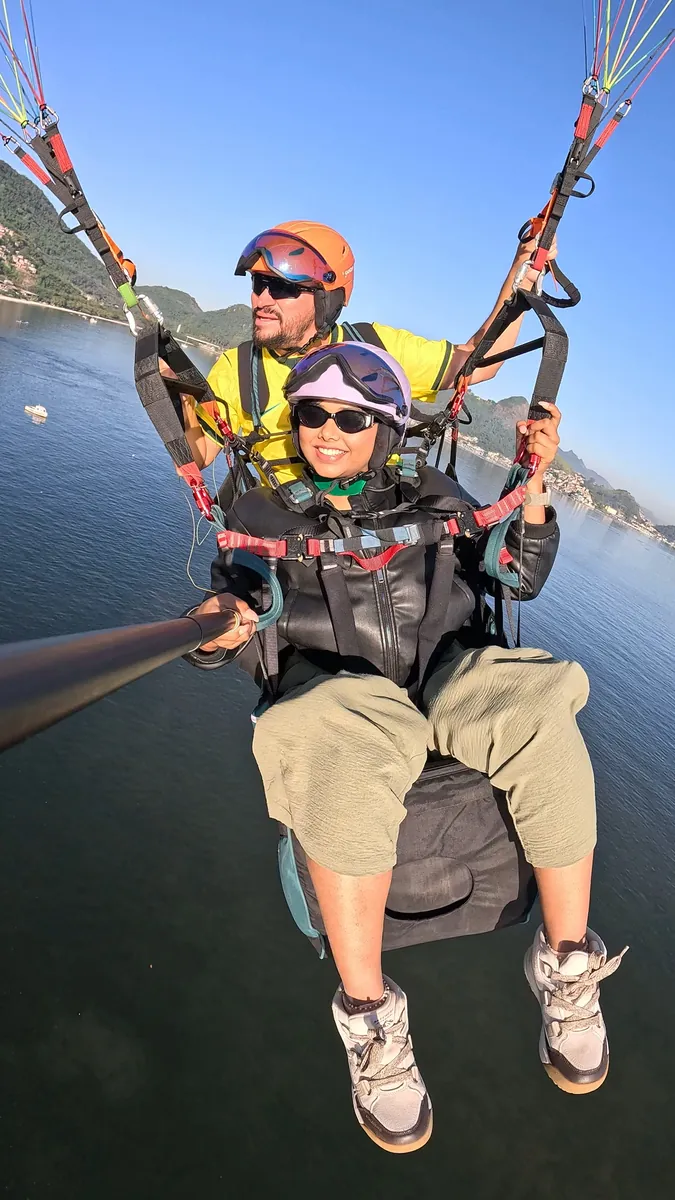 Casal de amigos em voo de parapente sobre Niterói