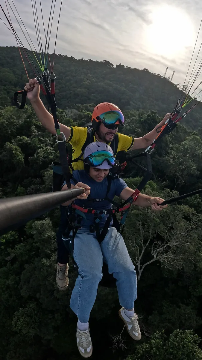 Parapente sobrevoando as casas e a mata de Niterói