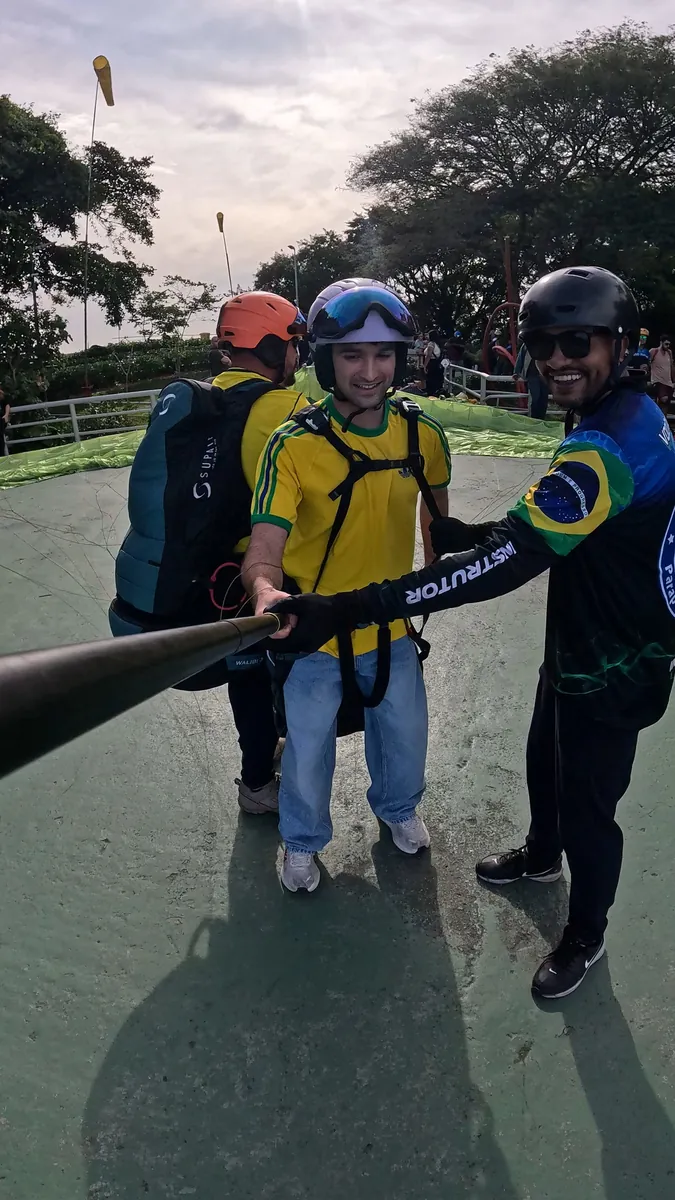 Passageiro com capacete e equipamento durante o voo de parapente